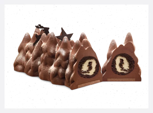 A luscious Buche De Noel Hazelnut Yule Log by PIERRE AND MICHEL, featuring a winter forest design. Layers of dark chocolate mousse, hazelnut filling, and a chocolate hazelnut crunchy biscuit create a festive delight.